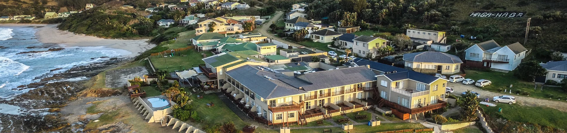Coastal houses overlook a sandy beach, with gentle waves and a bright sky creating a picturesque seaside scene. Coastal houses overlook a sandy beach, with gentle waves and a bright sky creating a picturesque seaside scene.
